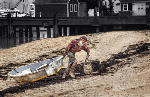 photo of a sailor pulling a boat into shore