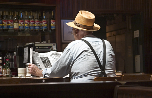 photograph of a man at a bar reading the paper