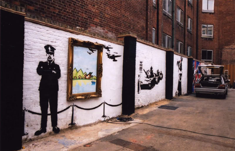 Banksy Cargo exhibition wall in London with a police figure and framed painting