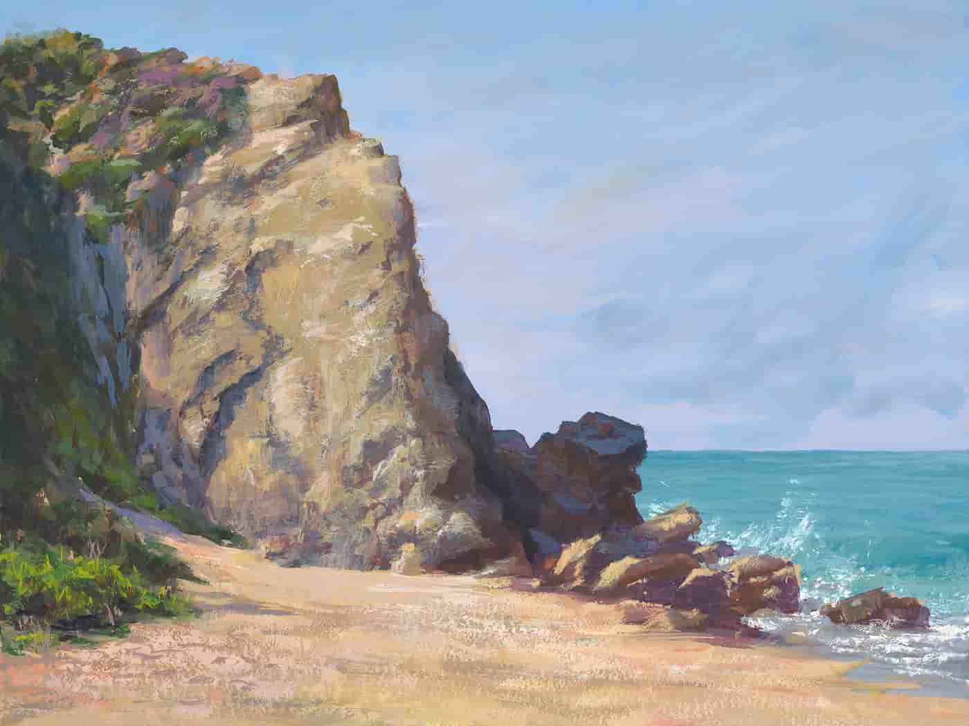 Rocky cliff jutting up from the sand with a bit of ocean and sky in the distance.